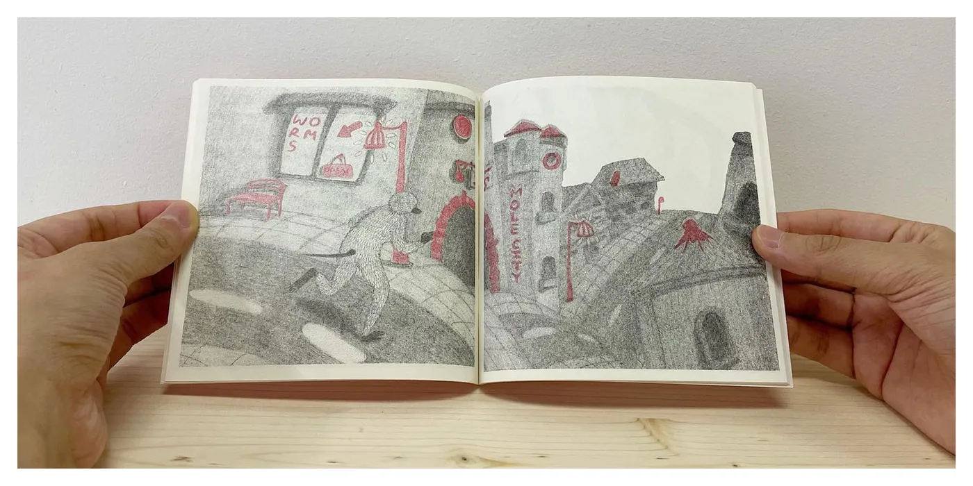 Hands holding Mole Story open on a spread of the mole city